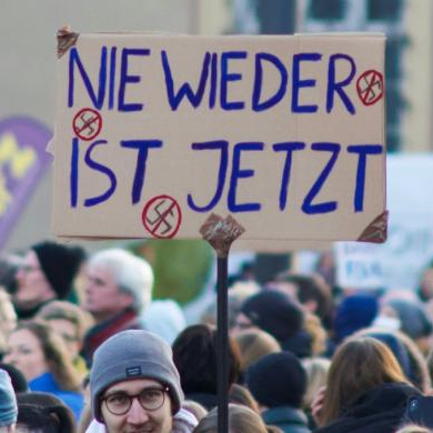 Großes Schild "Nie wieder ist jetzt" bei einer Demonstration