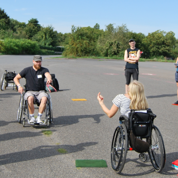 Teilnehmer*innen stehen bei strahlendem Sonnenschein auf dem Tempelhofer Feld und bekommen von den Workshopleiter*innen ein Spiel erklärt.