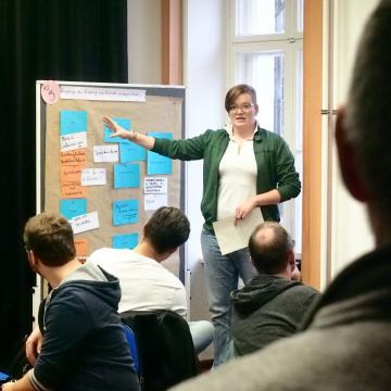 Jemand erklärt was an einem Flipchart vor Leuten bei einer Hauptausschuss-Klausur des Landesjugendring Berlin