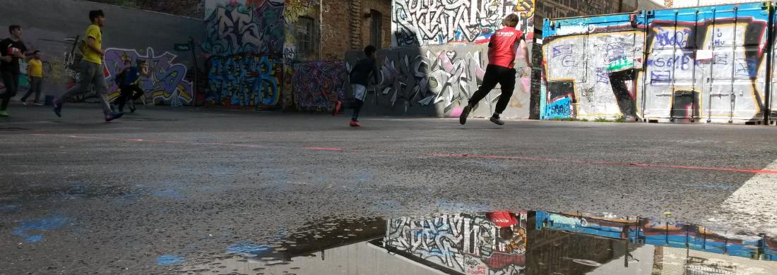 Auf Asphalt Fussball spielen Pfütze im Vordergrund