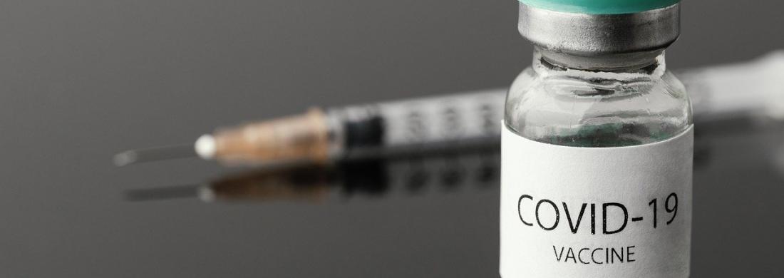 Ein Fläschchen mit COVID19-Impfstoff steht vor einer Spritze