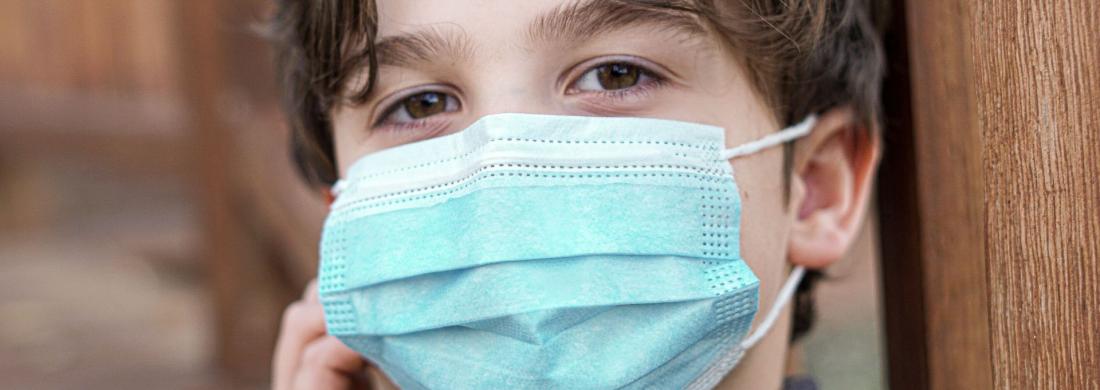 Ein etwa 10-jähriger Junge mit einem Mund-Nasen-Schutz in Nahaufnahme