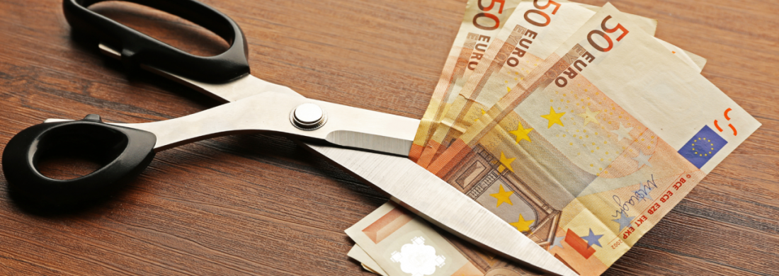 Drei 50-Euro-Scheine werden von einer großen Schere zerschnitten