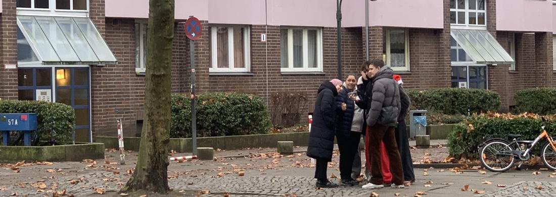 5 Jugendliche stehen nah beieinander, sind von weitem abgebildet