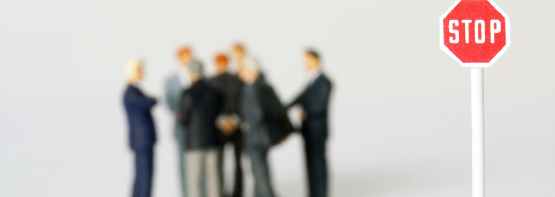 Stop-Schild im Vordergrund, eine Gruppe Menschen in Anzügen im Hintergrund