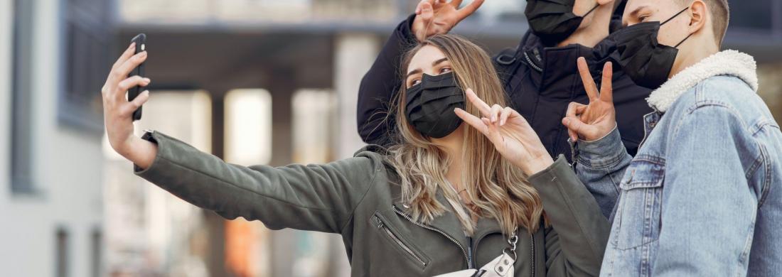 drei jugendliche mit Maske machen ein Selfie