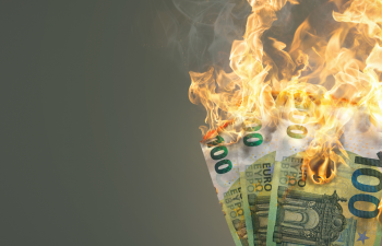 Im Fokus vor graumen Hintergrund: Drei 100-Euro-Geldscheine, die brennen.