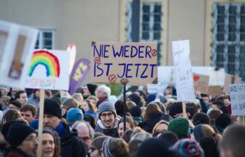 Eine große Gruppe von Menschen bei einer Demonstration. Auf einem Schild in der Mitte steht "Nie wider ist jetzt!"