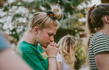 Junge Frau mit geschlossen Augen wirkt nachdenklich – Symbol für Unsicherheit und Belastung.