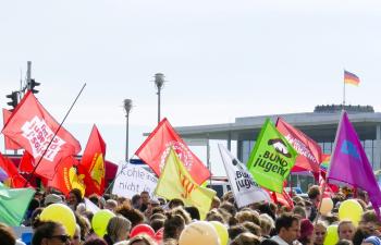 Vor dem Bundestag demonstrieren junge Menschen. Es sind viele Fahnen von verschiedenen Jugendverbänden und Sozialverbänden zu sehen.