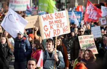 Demonstration gegen Kürzungen in Berlin, Menschen mit Plakaten und Fahnen auf der Straße.