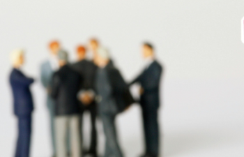 Stop-Schild im Vordergrund, eine Gruppe Menschen in Anzügen im Hintergrund