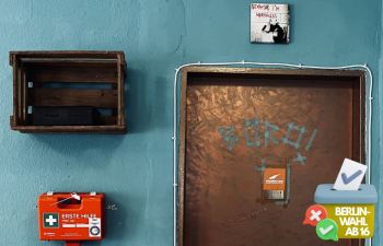 Tür mit Aufschrift "Büro", daneben ein Erste-Hilfe-Kasten, offene Stromleitungen und ein Schild auf dem "Because I'm worthless / Weil ich wertlos bin" steht)