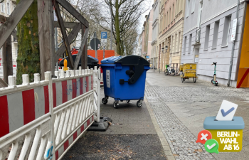 Müllcontainer blockiert schmalen Radweg, auf den ein Bauzaun ragt.