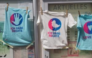 Drei T-Shirts auf einer Wäscheleine, die Kinder mit den Worten "Wir haben Rechte" bedruckt haben