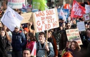 Demonstration gegen Kürzungen in Berlin, Menschen mit Plakaten und Fahnen auf der Straße.