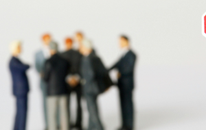 Stop-Schild im Vordergrund, eine Gruppe Menschen in Anzügen im Hintergrund