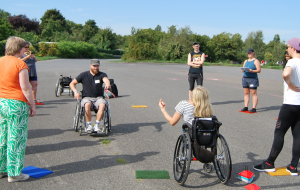 Teilnehmer*innen stehen bei strahlendem Sonnenschein auf dem Tempelhofer Feld und bekommen von den Workshopleiter*innen ein Spiel erklärt.